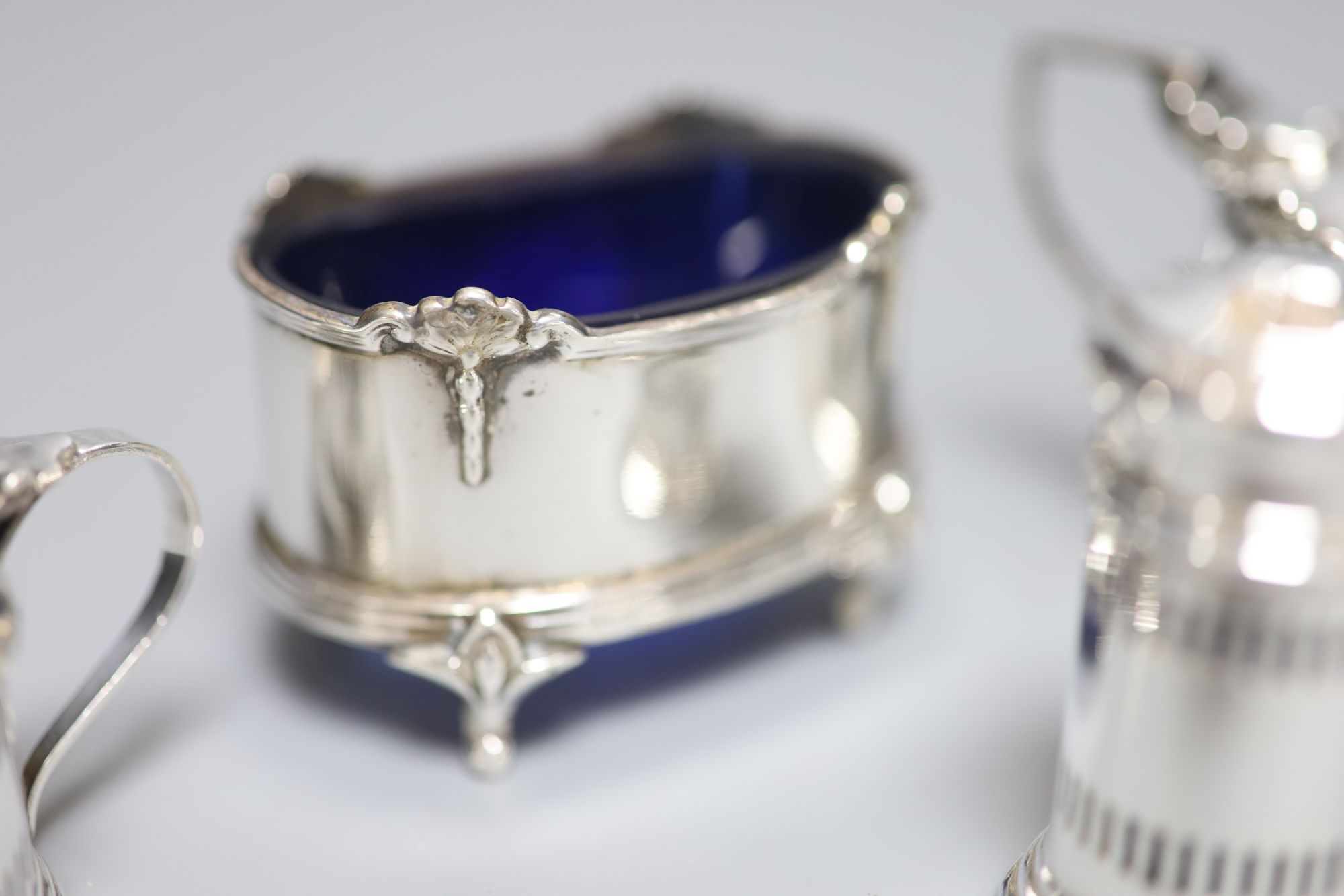 A George V small silver three piece condiment set, Birmingham, 1932 and two other silver condiments.